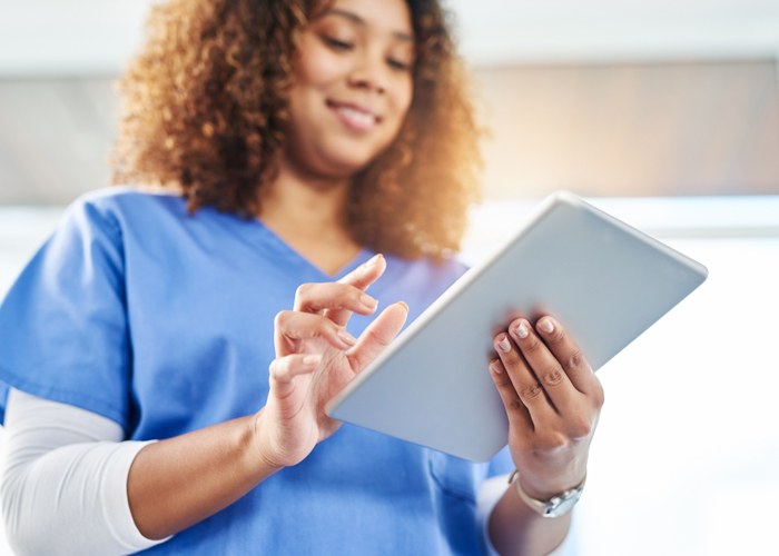 Nurse with scrubs on working on an ipad